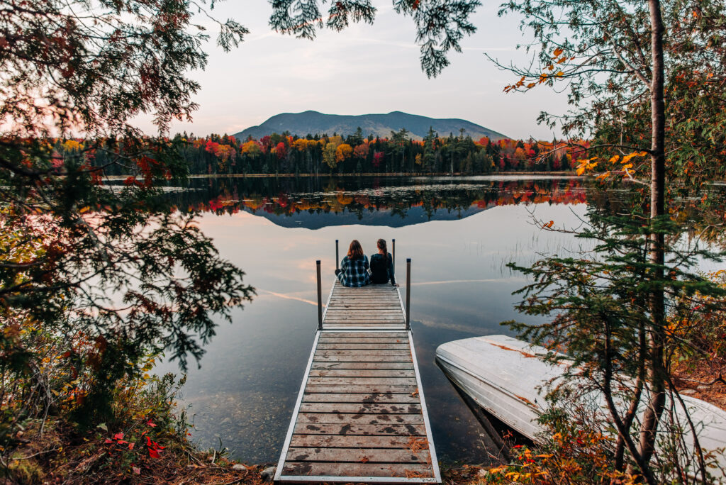 Two people looking out from a dock at sunset.