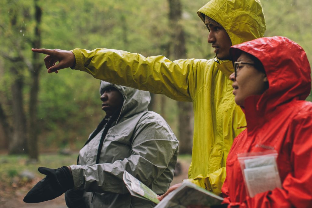 Hikers in colorful rain jackets pointing to the distance.