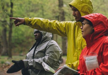Hikers in colorful rain jackets pointing to the distance.