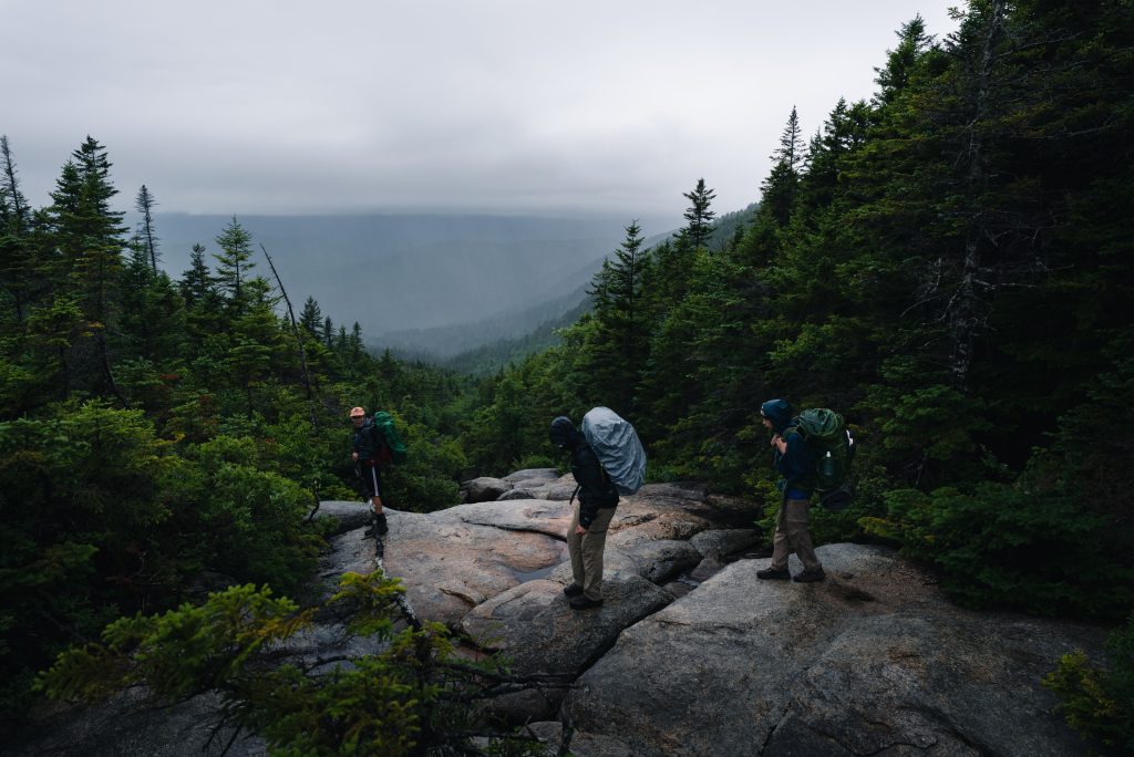 Hikers hiking with backpacks on a peak at dusk.
