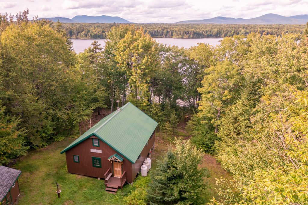Brown cabin next to a lake.