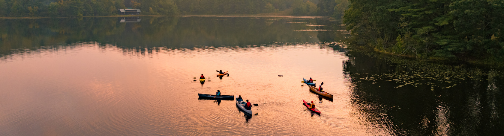 Page Header Desktop (3) aerial view of kayaks and canoes on pond at sunset