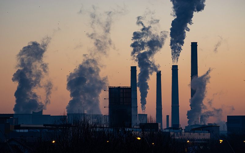 Factory smokestacks silhouetted against the sunset