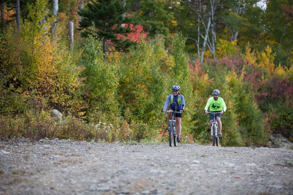 Smiling people biking on the gravel roads in Maine's 100-mile wilderness