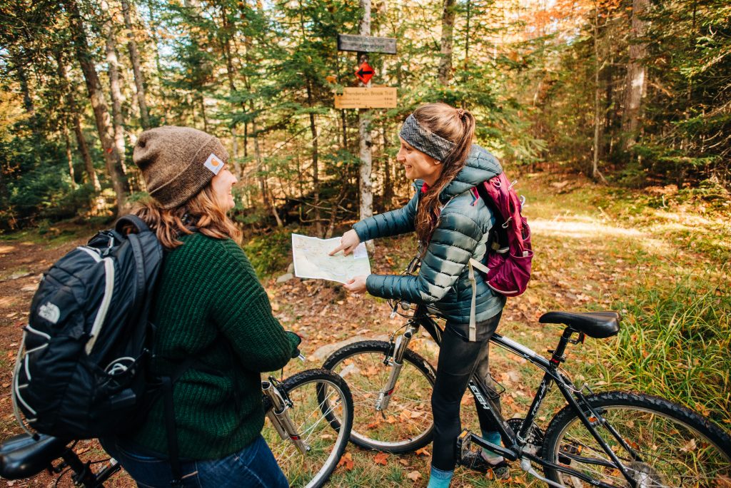 Two people on bikes smiling and pointing to a map.