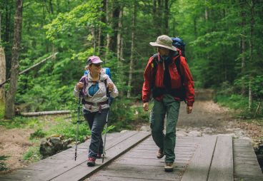Two hikers walking on a wide bridge.