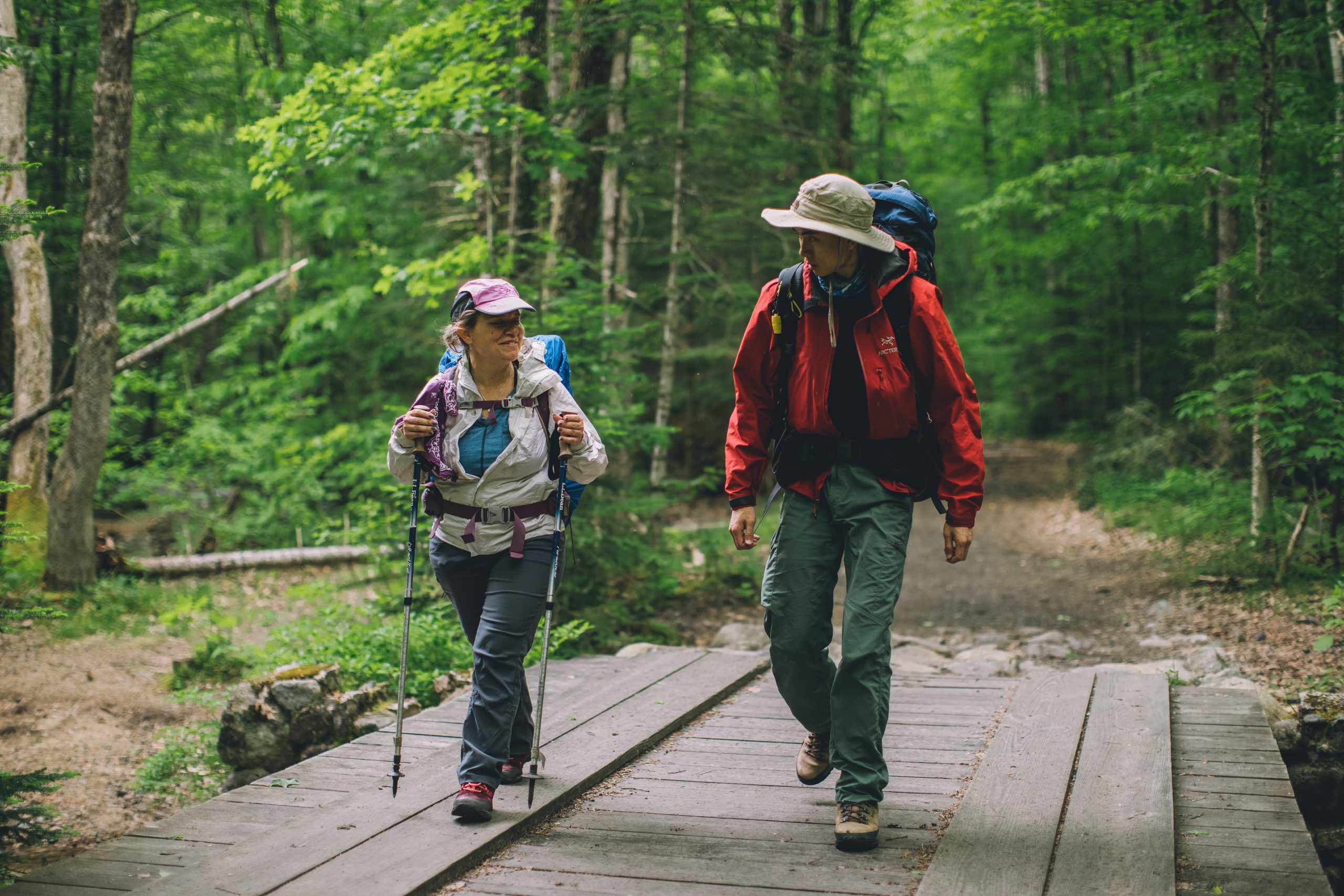 Two hikers walking on a wide bridge.