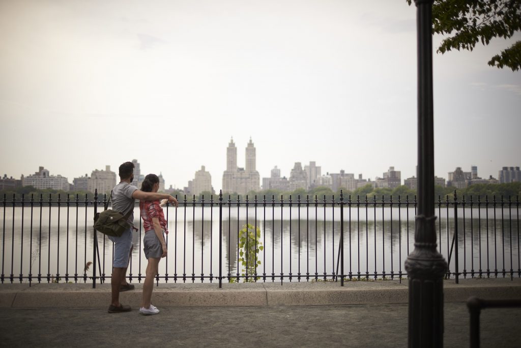 A couple stands in front of the NYC skyline in Brooklyn.