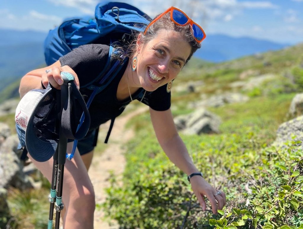 Bethany Taylor with a backpack, smiling above treeline.