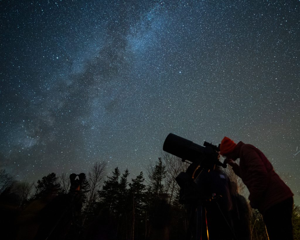 Person looking at the sky through a telescope.