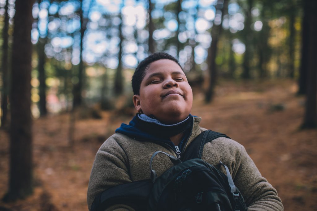 Kid with eyes closed, deep breathing in the outdoors.