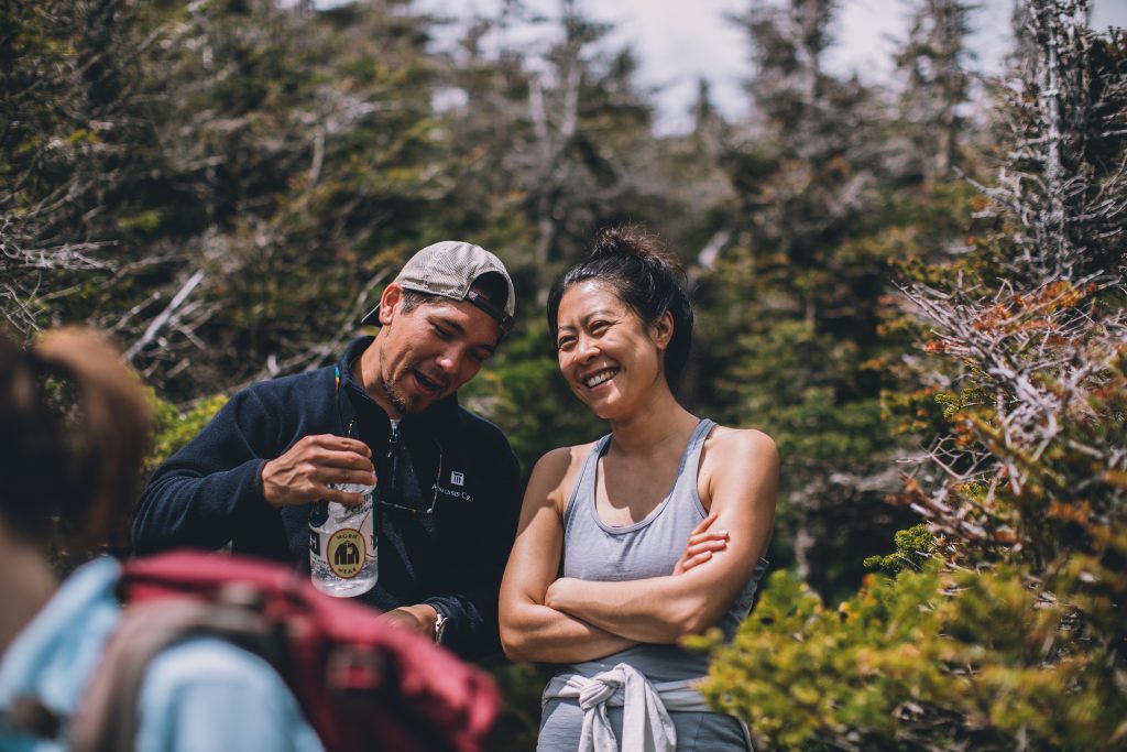 A couple laughing outside while on a hike.