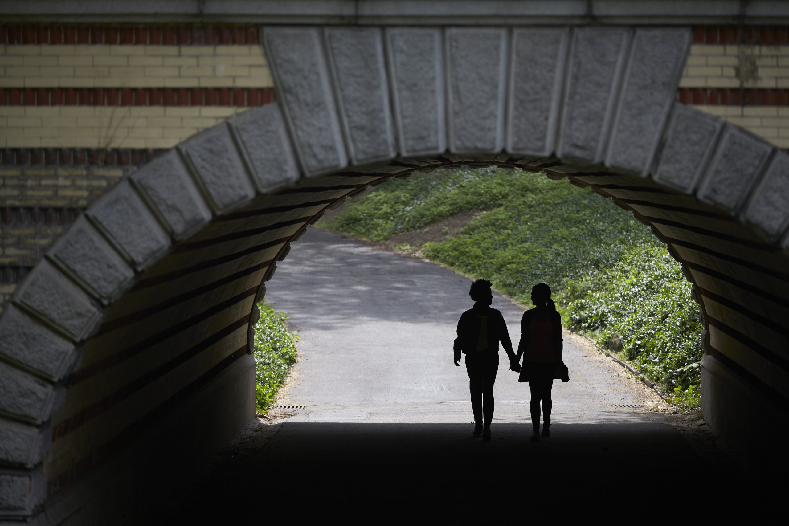 Silhouetted couple holding hands under a bridge in Central Park.