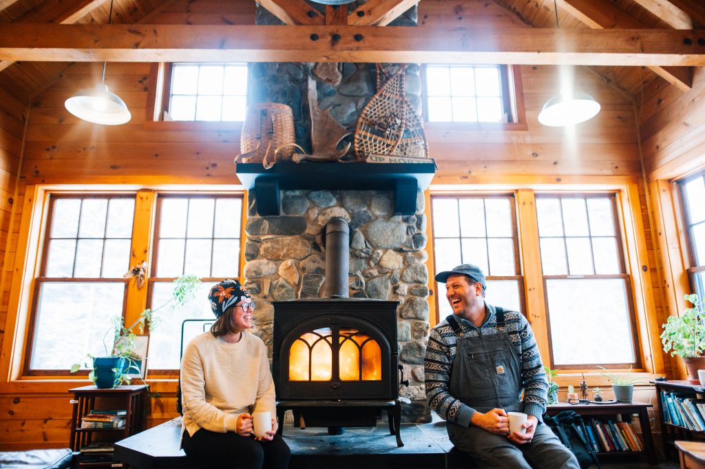 Two people sitting on the hearth in front of a roaring fire.