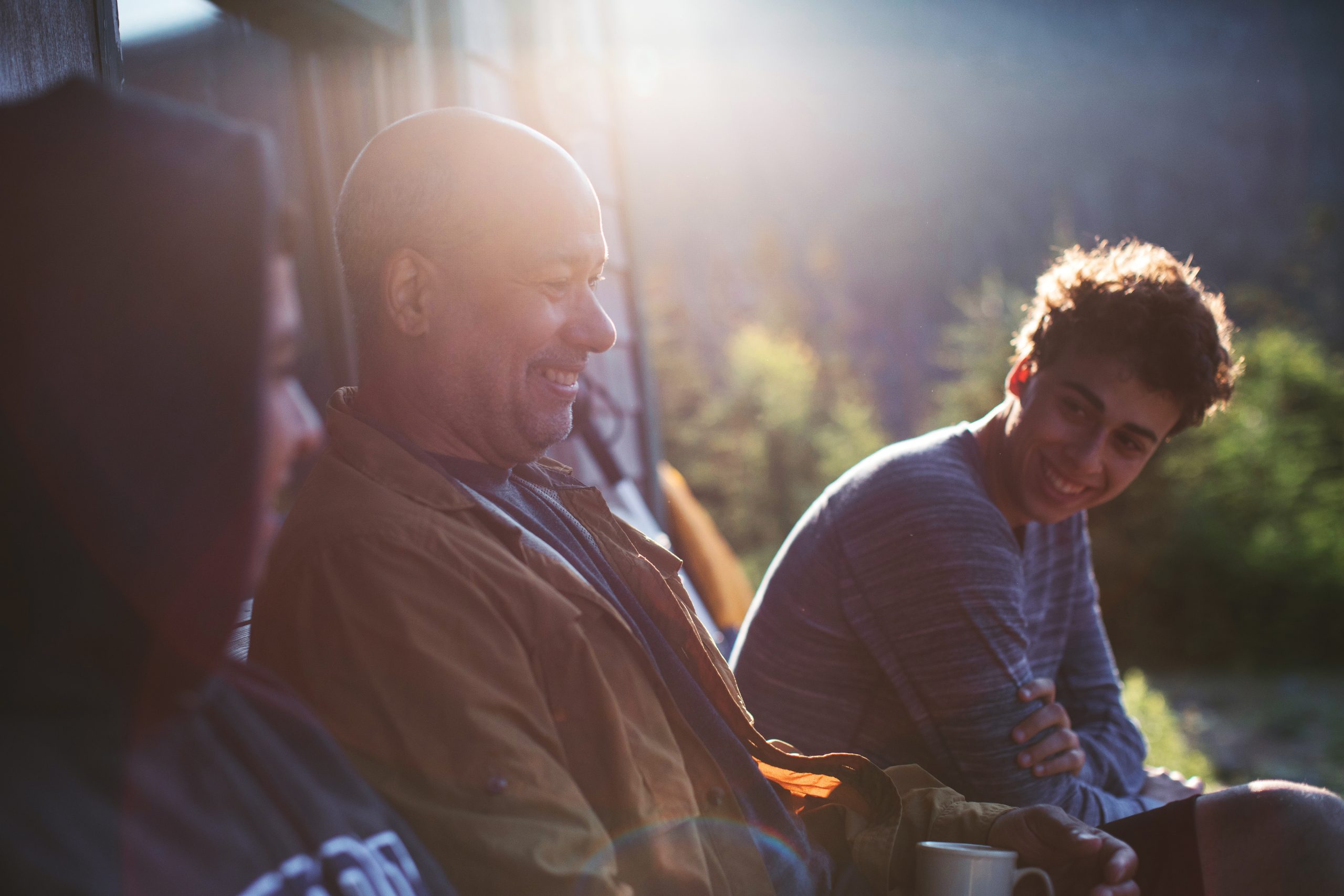 Smiling people outside a hut in the sun.