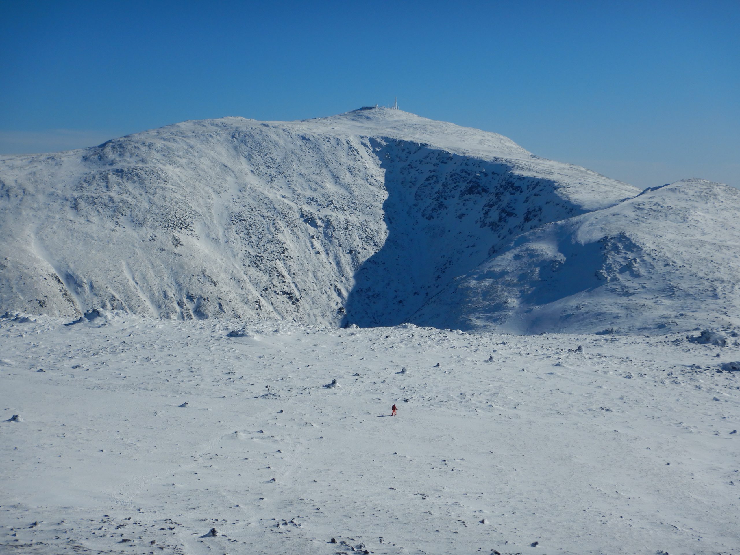 The snowy shoulder of a mountain framed by blue sky.