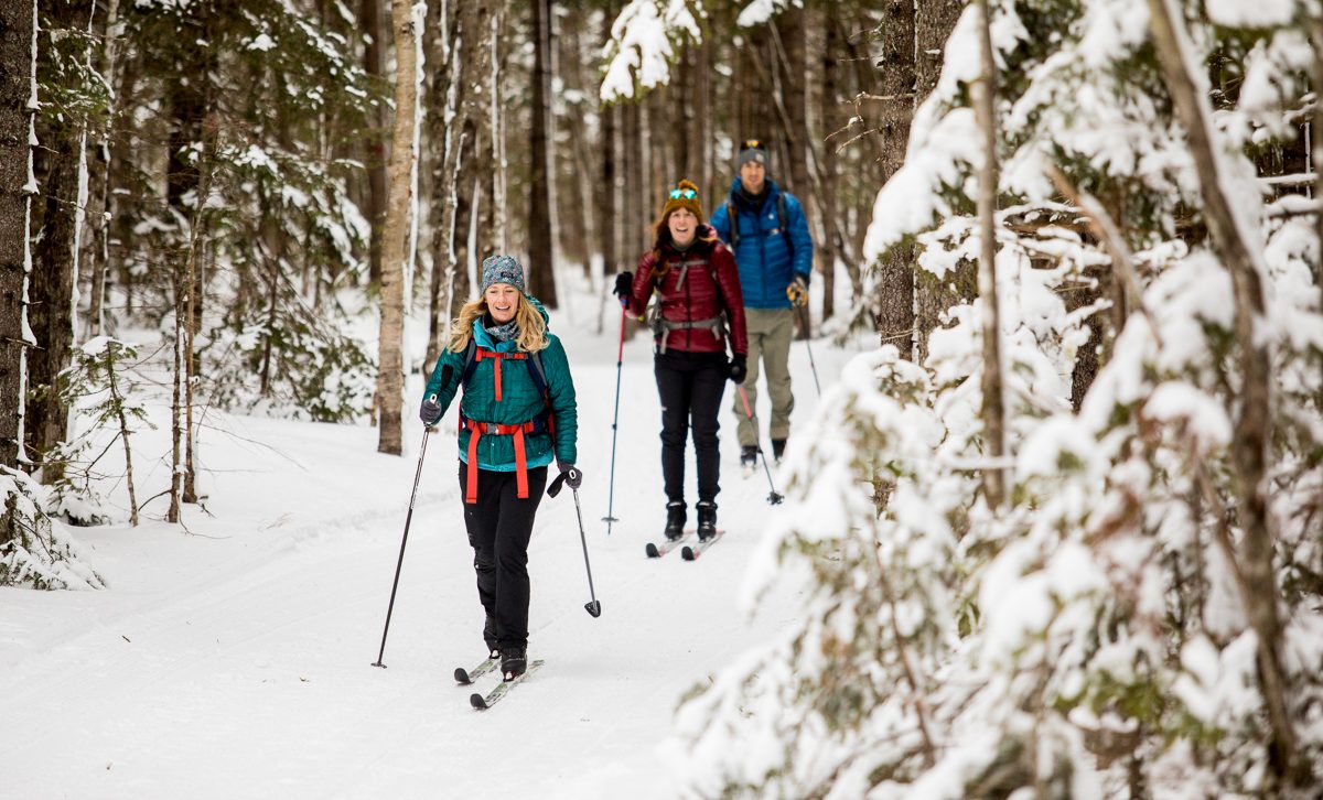 Three people lodge-to-lodge skiing in the Maine Woods