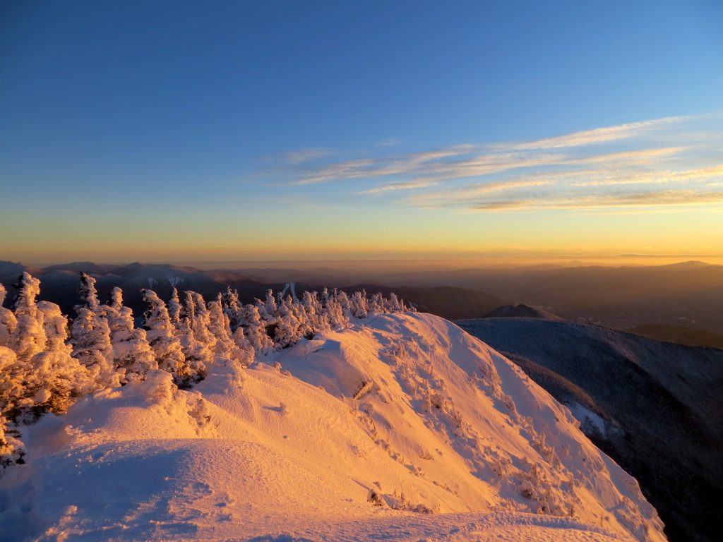 A snow-covered mountain is lit up by a beautiful sunrise.