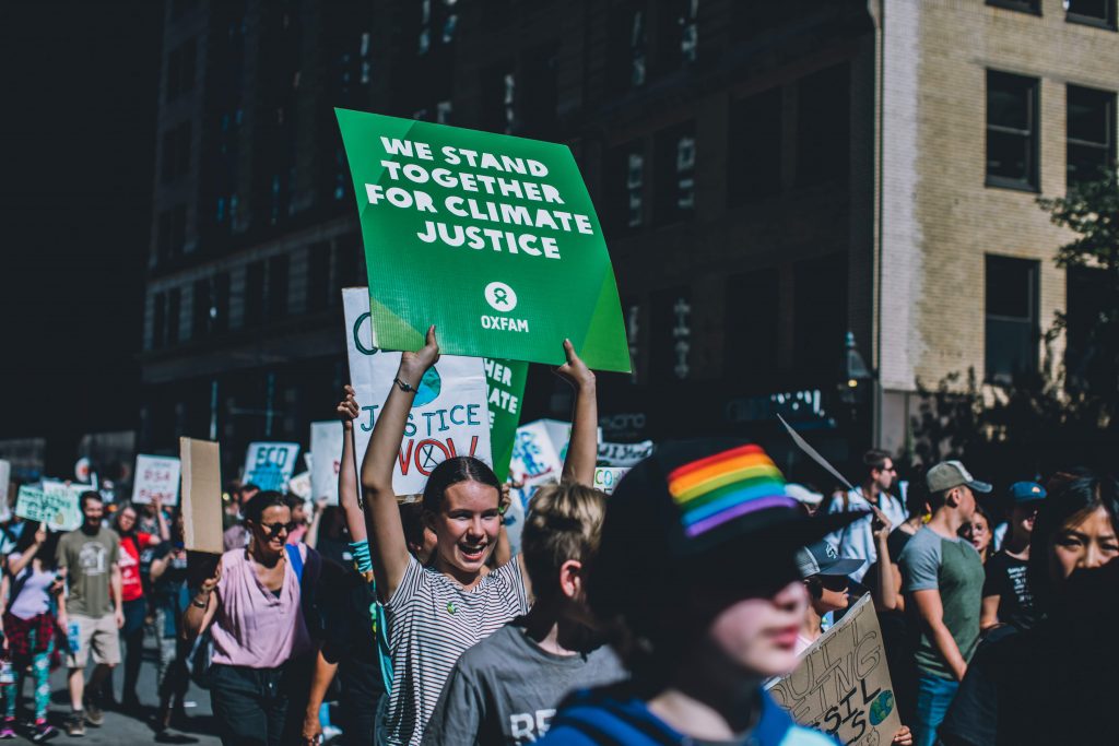 Young protesters march in the Global Climate Strike. One holds a sign that reads, "We Stand Together For Climate Justice."