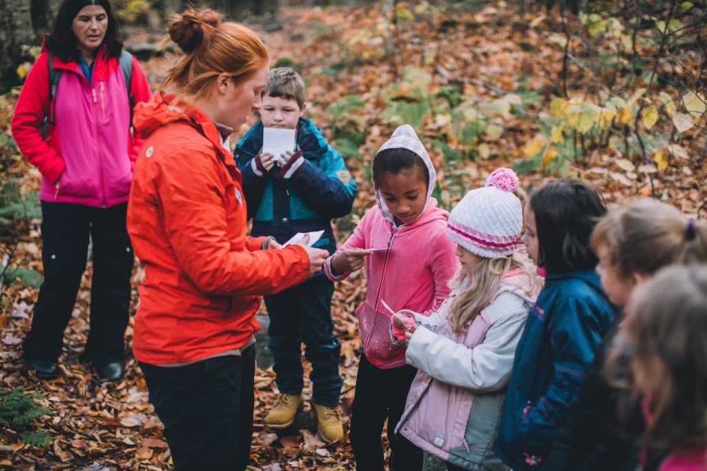 A group of children are guided by AMC staff through handouts as they explore the forest.