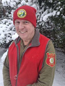 Mark Warren smiling in a red vest and AMC beanie.