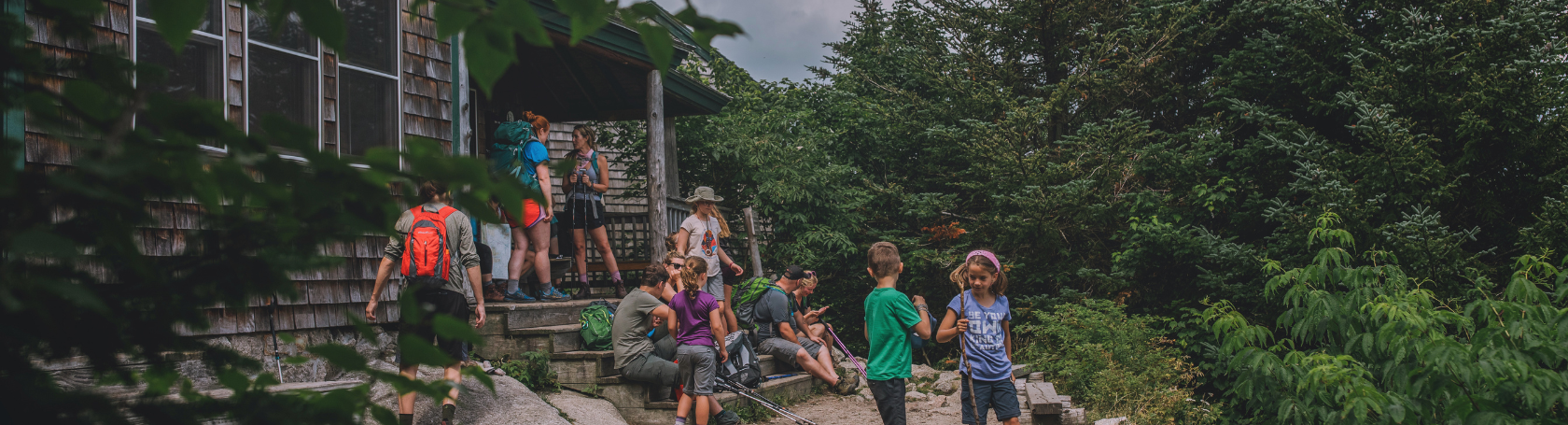 Page Header Desktop (1) People outside a hut with backpacks on.