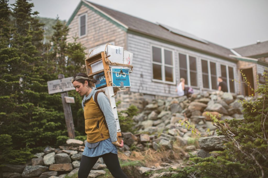 Hut Croo member carrying a packboard.