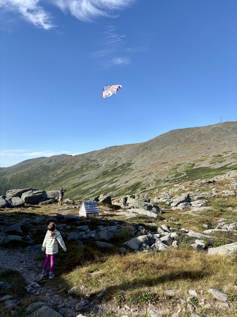 Girl and her dad flying a kite in front of Mt. Washington.